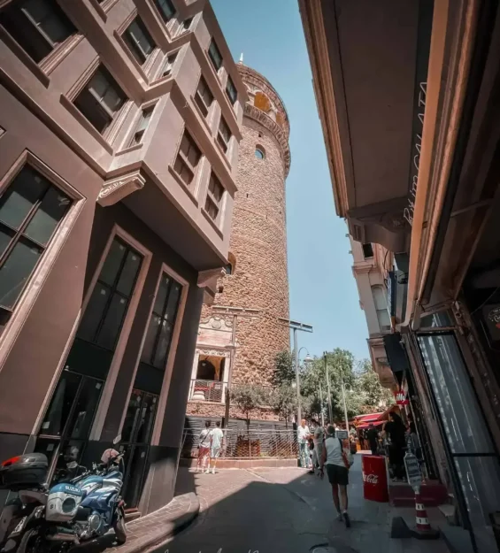 İstanbul'un dar bir sokağından görülen Galata Kulesi. Tarihi Galata mimarisi, ikonik kuleyi çevreliyor. _by fotoloji
