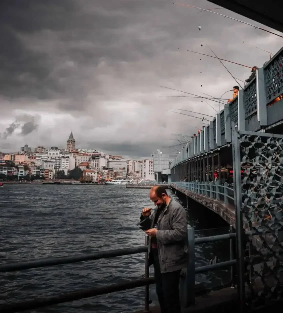 İstanbul'daki Galata Köprüsü'nde, Galata Kulesi ve tarihi şehir manzarasına bakan adam. _by fotoloji