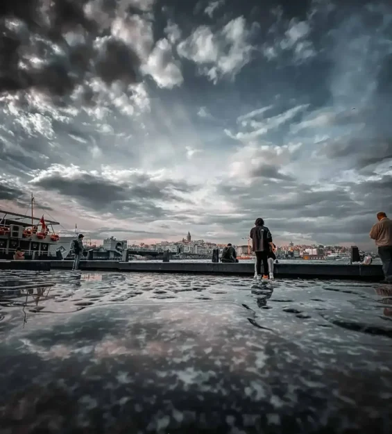 İnsanlar, yansıtıcı bir su yüzeyinin üzerinden Galata Kulesi'nin gün batımı manzarasının tadını çıkarıyor _by fotoloji
