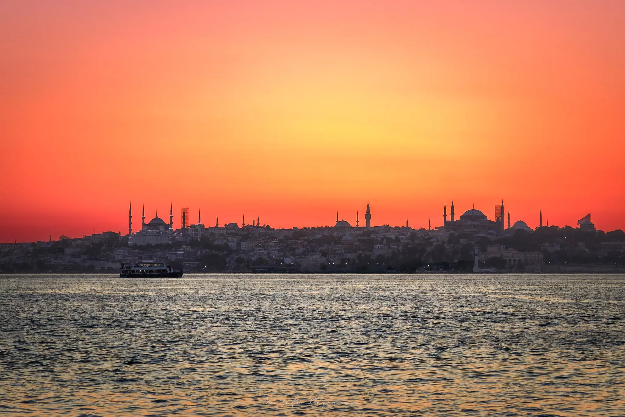 Gün Batımı: Gökyüzünün Dansı 1 Canlı bir gün batımının önünde silüet halinde görünen İstanbul silüeti. Romantik bir gün batımı atmosferi.