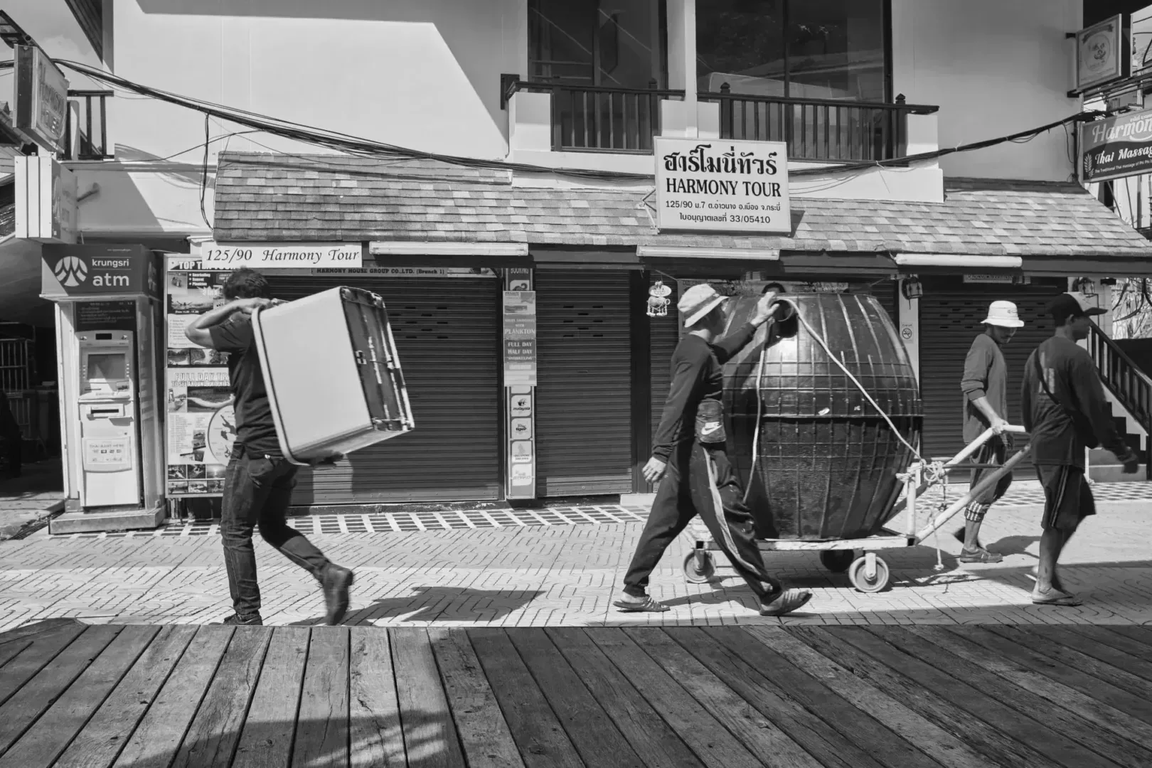 grayscale photo of man and woman walking on wooden pathway