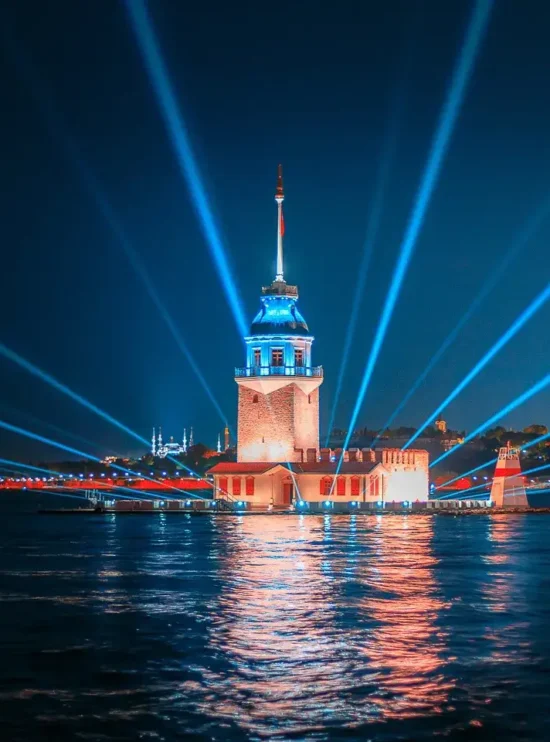 Istanbuldaki Kiz Kulesi Gece Gokyuzune Yayilan Isinlar Ve Sudaki Yansimalarla Mavi Isiklarla Aydinlatilmis