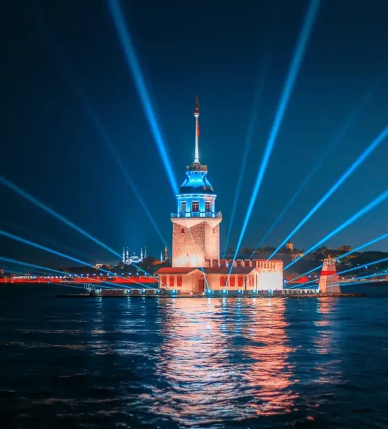 Istanbuldaki Kiz Kulesi Gece Gokyuzune Yayilan Isinlar Ve Sudaki Yansimalarla Mavi Isiklarla Aydinlatilmis