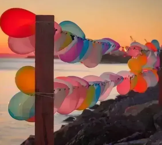 Colorful balloons strung along seaside fence