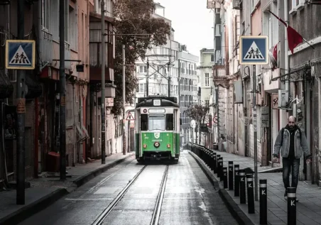Yesil Bir Tramvay Eski Binalarin Arasindaki Dar Bir Sokaktan Geciyor Kaldirimda Ise Bir Kisi Yuruyor Yesil Bir Tramvay Eski Binalarin Arasindaki Dar Bir Sokaktan Geciyor Kaldirimda Ise Bir Kisi Yuruyor