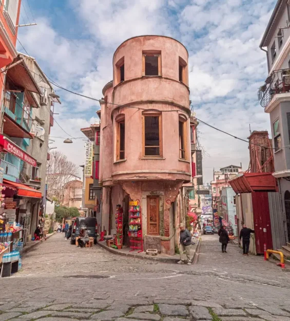 Türkiye'nin İstanbul şehrinde, rengarenk binaların ve eşsiz yuvarlak kule evin bulunduğu dar, Arnavut kaldırımlı sokak. by fotoloji