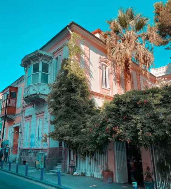 Pastel pembe renkli, süslü balkonlu, yemyeşil bitki örtüsü ve palmiye ağaçlı tarihi bina. by fotoloji