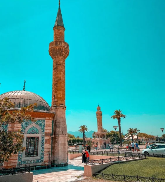 Canlı mavi gökyüzünün altında yüksek minaresi ve saat kulesi olan bir cami. by fotoloji