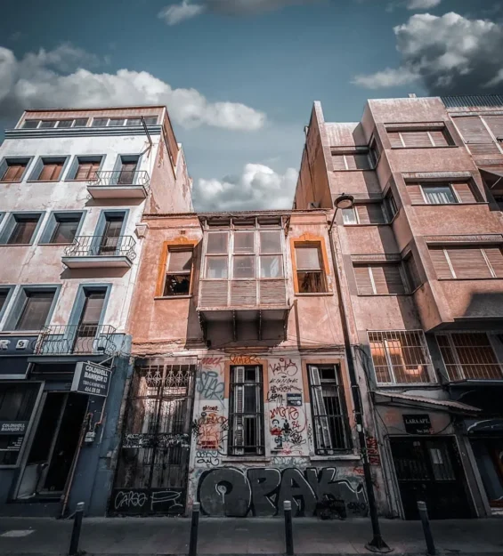 İki yüksek bina arasında grafiti kaplı terk edilmiş bina, kentsel çürüme, sokak sanatı by fotoloji