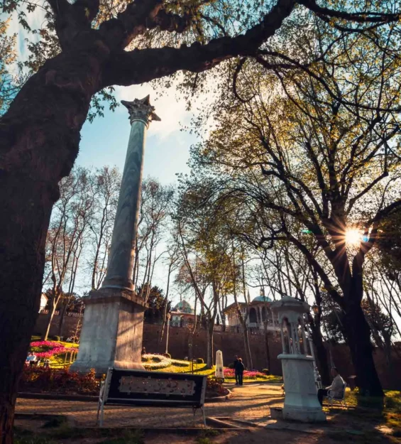 İstanbul parkındaki antik mermer sütun, ağaçların arasından süzülen güneş ışığı _by fotoloji