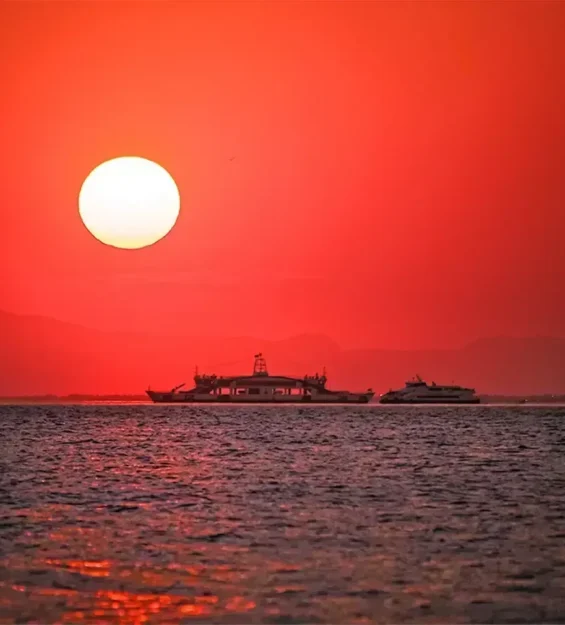 Canlı kırmızı gün batımı gökyüzünün altında okyanusta yelken açan tekne _by fotoloji