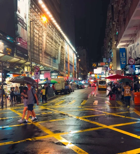 Hong Kong'da yağmurlu gece manzarası, canlı sokak yaşamını ve neon tabelaları gösteriyor. _by fotoloji