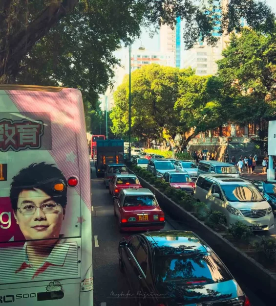 Hong Kong caddesinde trafik ve reklam panolarıyla çevrili ağaçlı yol, modern mimariyle çevrili _by fotoloji