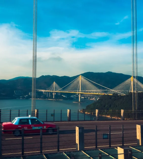 Hong Kong köprüsünde muhteşem liman ve dağ manzaraları eşliğinde kırmızı taksi. _by fotoloji