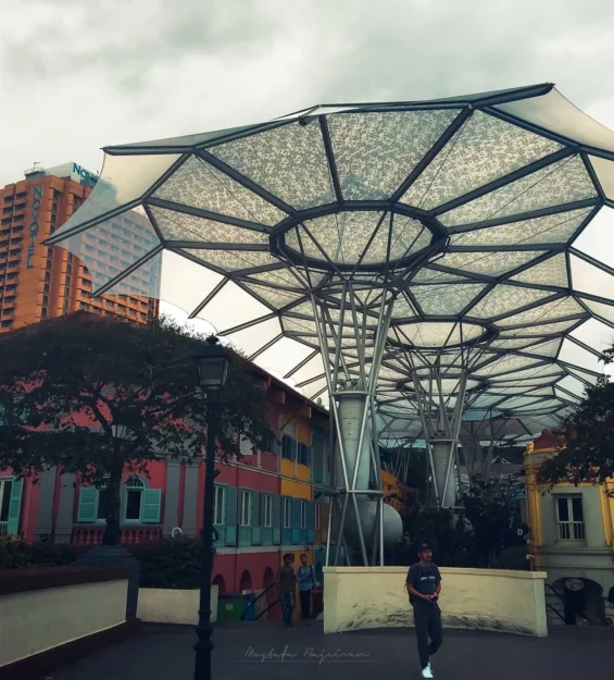 Renkli Singapur dükkanlarının üzerinde modern şemsiye benzeri yapı; Novotel görünüyor. _by fotoloji