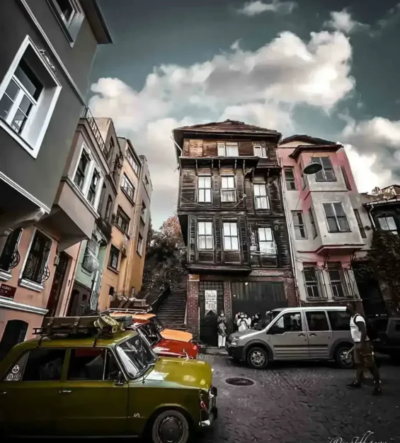 Türkiye'nin İstanbul şehrinde tarihi ahşap binaların bulunduğu Arnavut kaldırımlı bir sokakta park edilmiş klasik arabalar.