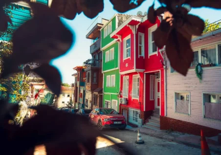 balat-00028 Türkiye, İstanbul'da bir yamaçta rengarenk evler. Sokakta kırmızı bir araba park edilmiş.