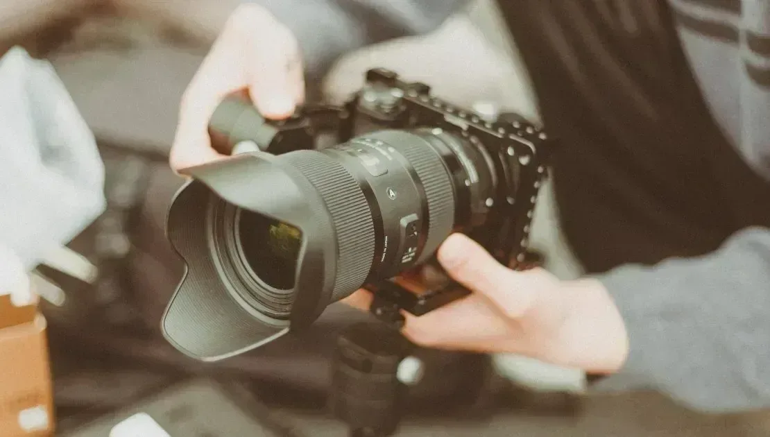 Fotoğraf Makinesi ve Lens Temizliği'nin vazgeçilmezi lensli fotoğraf makinesini tutan eller.