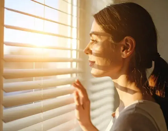 Woman looking out window at sunrise