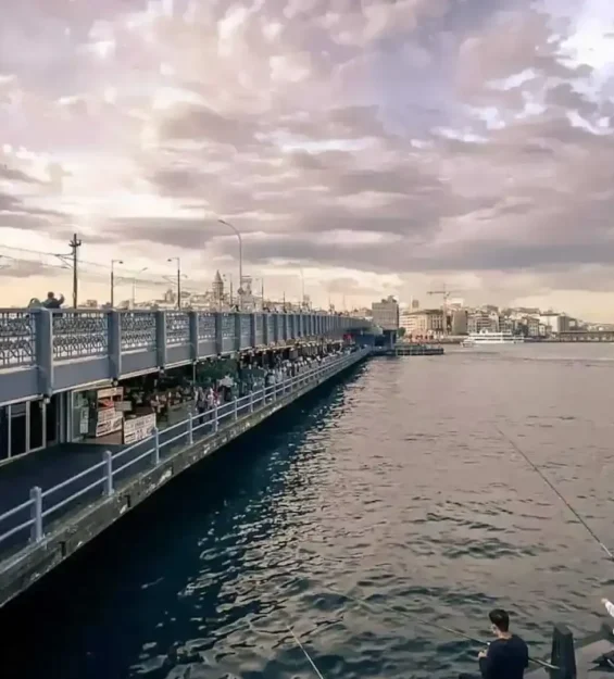 Türkiye'nin İstanbul kentindeki Galata Köprüsü'nde balık tutan ve köprü boyunca yürüyen insanlar.