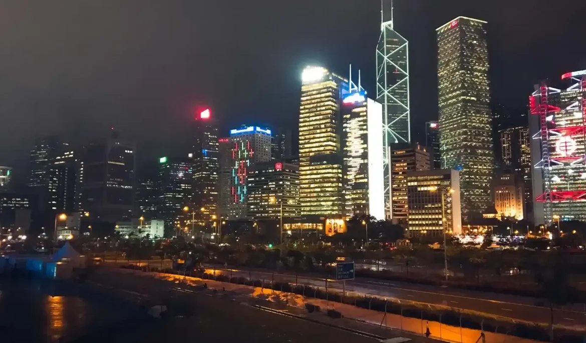 Hong Kong'un aydınlatılmış gökdelenleri ve şehir sokaklarının gece görünümü.