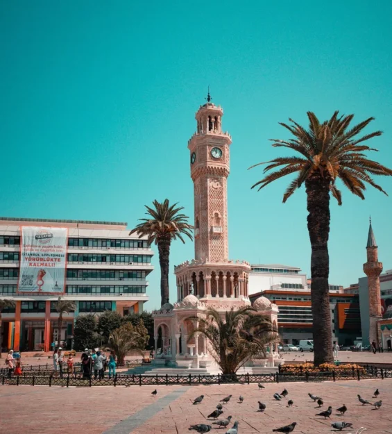 Türkiye'nin Konak Meydanı'nda bulunan, palmiye ağaçları ve güvercinlerle çevrili İzmir Saat Kulesi.