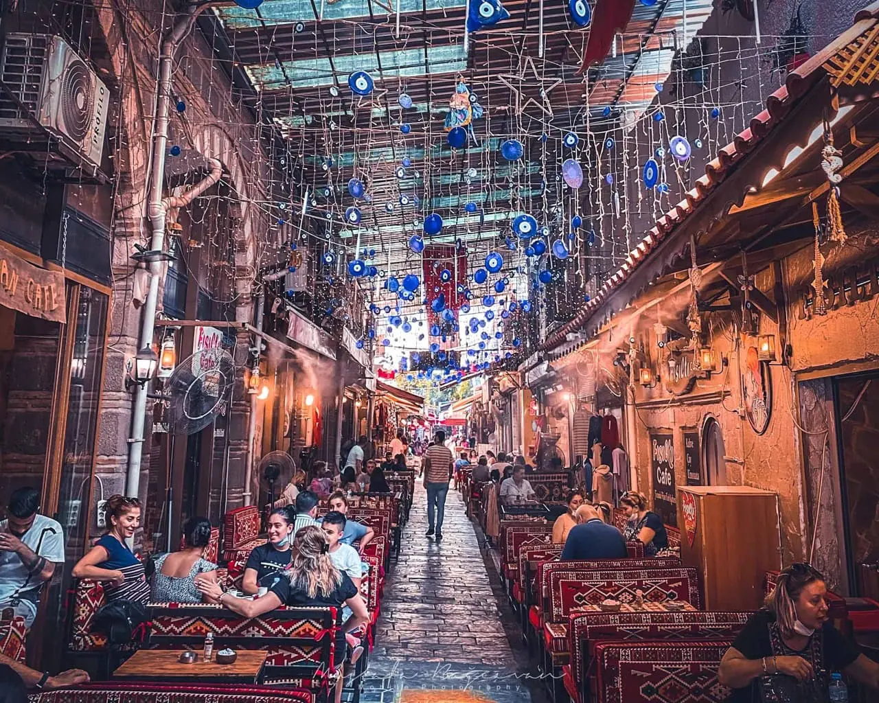 Mavi nazar boncuklarıyla süslenmiş, kafelerle çevrili dar Türk sokağı.