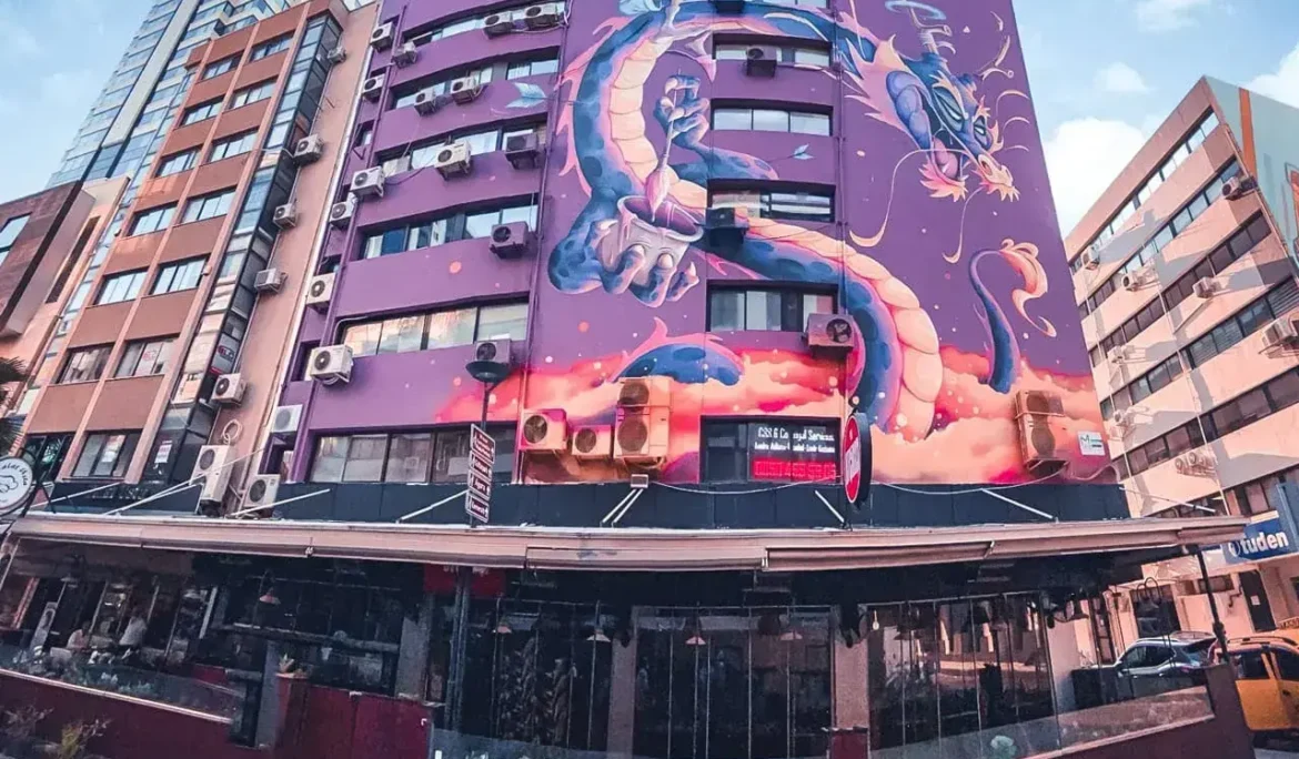 Bir binanın cephesinde ejderha ve kız çocuğunun yer aldığı büyük duvar resmi.