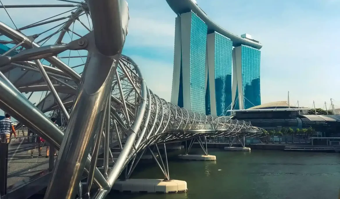 Arka planda Marina Bay Sands otelinin bulunduğu su üzerindeki modern yaya köprüsü.
