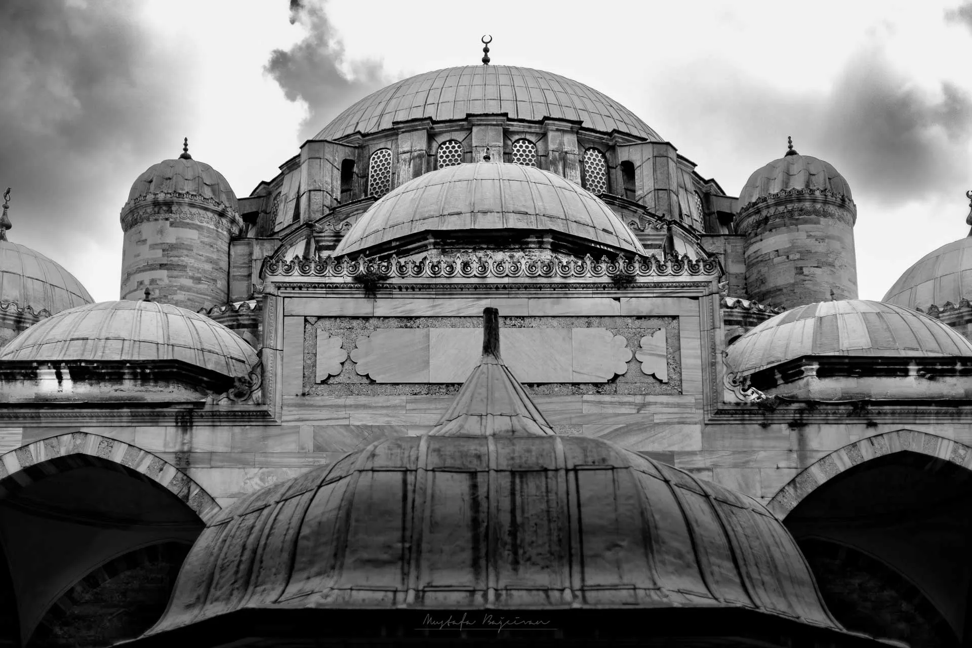 Bir caminin karmaşık kubbe ve minarelerinin siyah beyaz fotoğrafı.